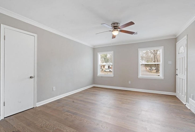 Empty room featuring crown molding, light hardwood / wood-style floors, new windows, and ceiling fan