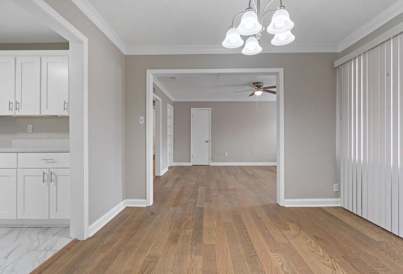 Unfurnished dining area with crown molding, light hardwood / wood-style floors, and ceiling fan with notable chandelier