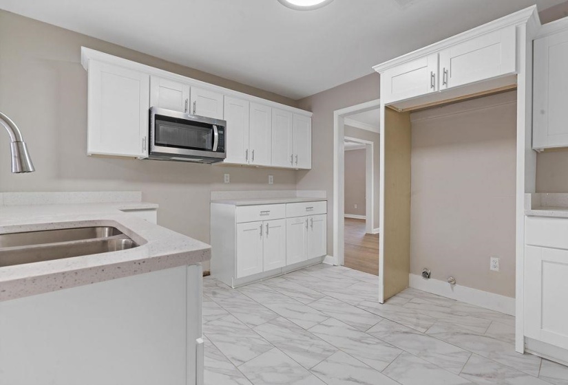 Kitchen with white cabinetry, sink, and quartz countertops