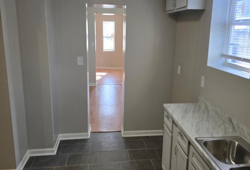 Kitchen with dark tile patterned flooring, sink, and white cabinetry