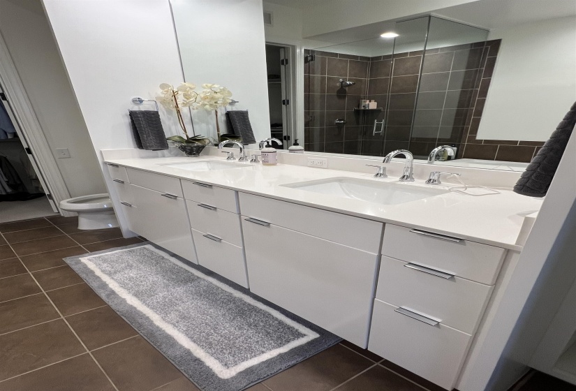 Bathroom with tiled shower, tile patterned floors, toilet, and vanity