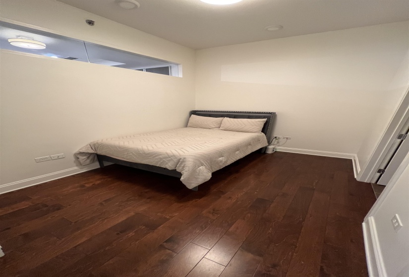 Bedroom with dark hardwood / wood-style flooring