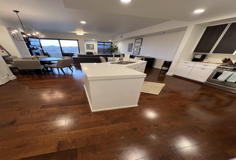Kitchen featuring stainless steel gas range, sink, dark hardwood / wood-style floors, an island with sink, and pendant lighting