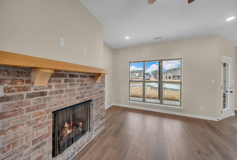 Unfurnished living room featuring a ceiling fan, a fireplace, wood finished floors, baseboards, and recessed lighting