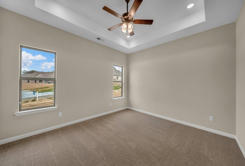 Unfurnished room featuring visible vents, carpet, baseboards, a ceiling fan, and a raised ceiling