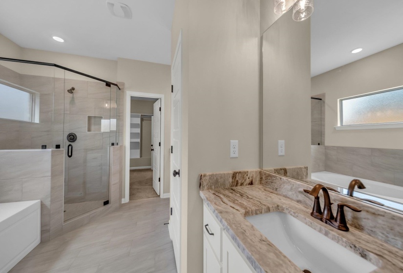 Full bath with a shower stall, a spacious closet, vanity, and a bath