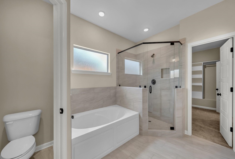 Full bathroom with a stall shower, vaulted ceiling, toilet, a garden tub, and baseboards
