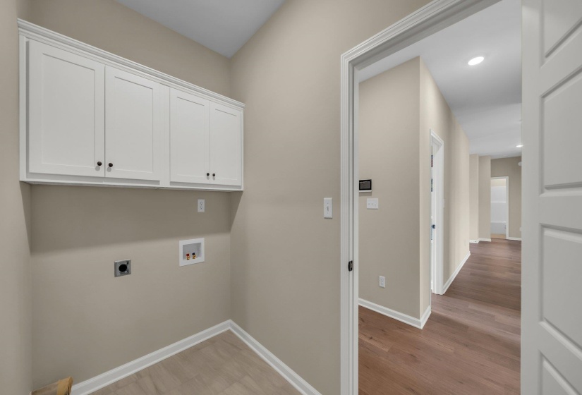 Clothes washing area featuring hookup for a washing machine, baseboards, light wood-style floors, electric dryer hookup, and cabinet space