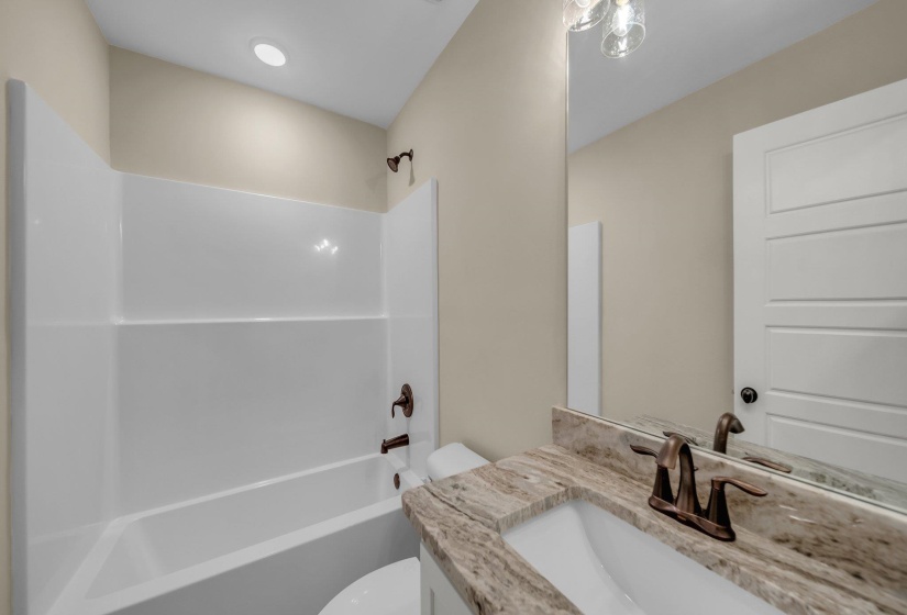 Bathroom featuring toilet, vanity, and washtub / shower combination