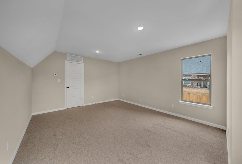 Interior space featuring lofted ceiling, recessed lighting, baseboards, carpet floors, and visible vents