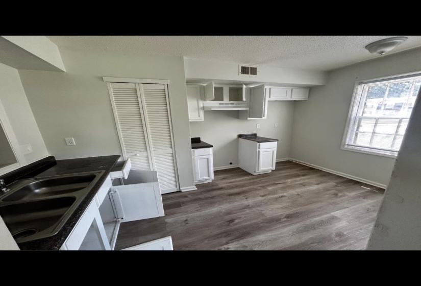 Kitchen featuring dark countertops, visible vents, a sink, a textured ceiling, and wood finished floors