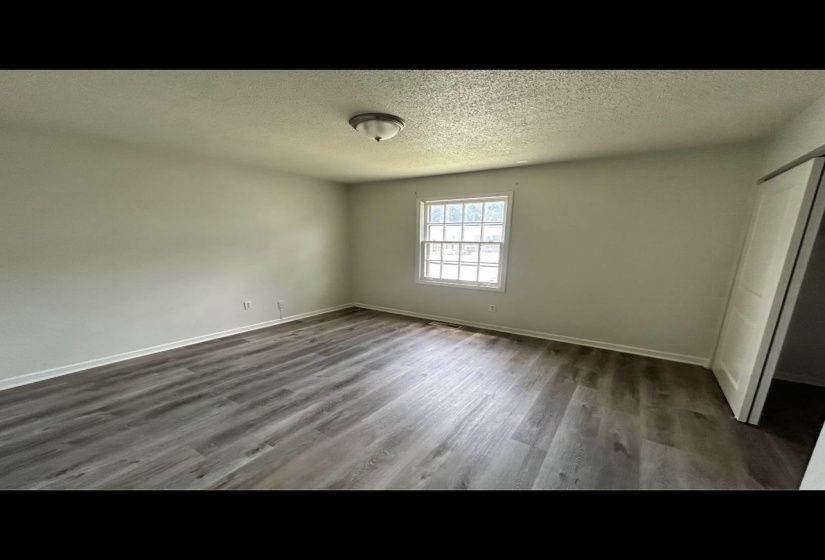 Unfurnished bedroom with a closet, a textured ceiling, baseboards, and wood finished floors