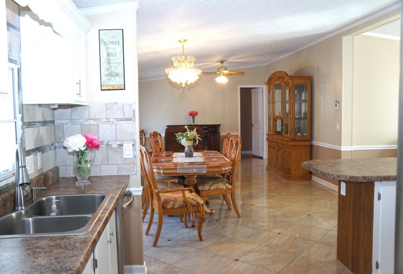 Kitchen featuring a textured ceiling, ornamental molding, a sink, and white cabinets