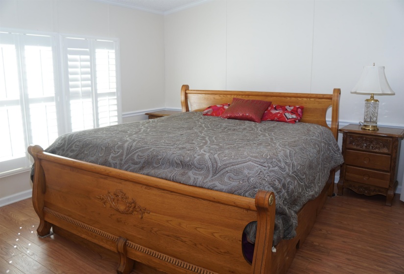 Bedroom with multiple windows, wood finished floors, and crown molding
