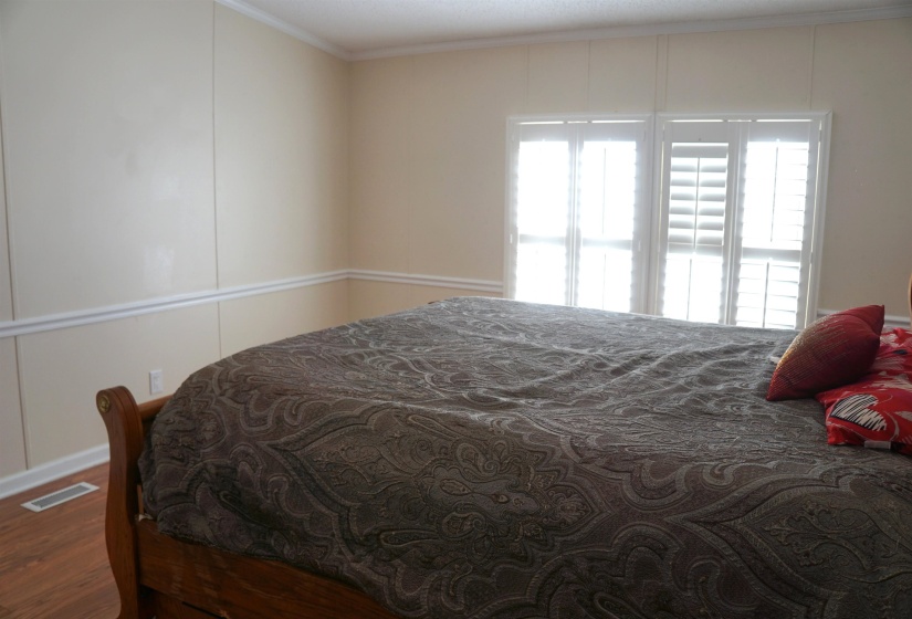 Bedroom featuring visible vents, wood finished floors, and ornamental molding