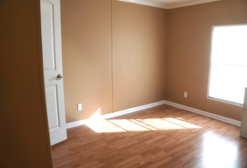 Spare room featuring crown molding, baseboards, and wood finished floors