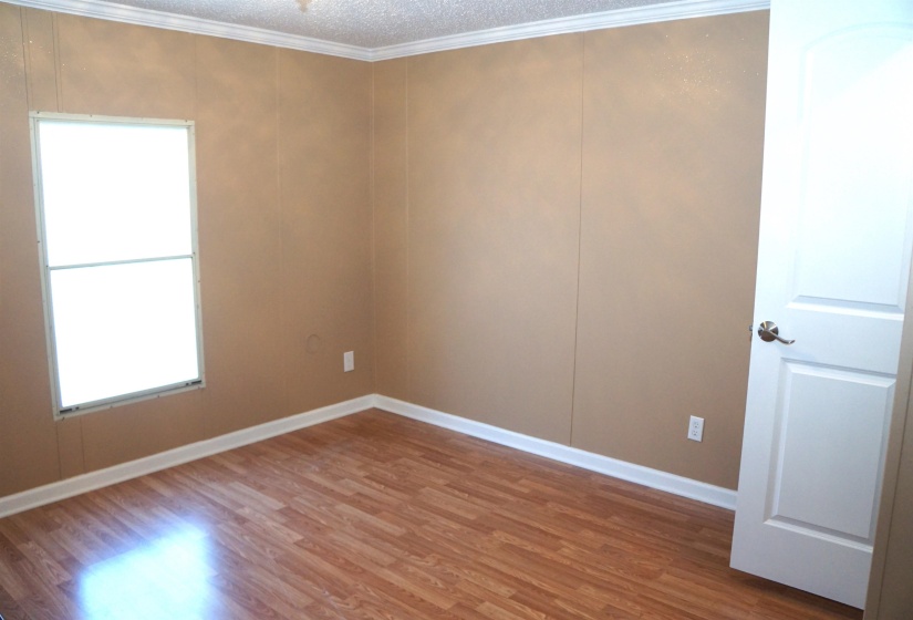 Spare room featuring baseboards, a textured ceiling, ornamental molding, and wood finished floors