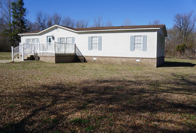 View of front facade with a front lawn, crawl space, and a wooden deck