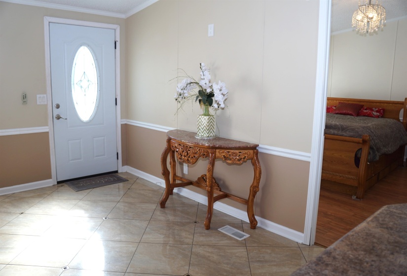 Entrance foyer with baseboards, light tile patterned floors, visible vents, and crown molding