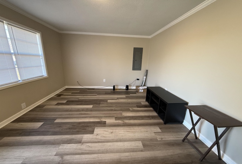 Spare room with electric panel, crown molding, baseboards, and wood finished floors