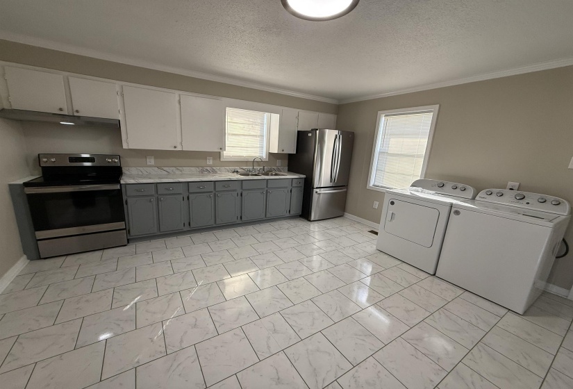 Kitchen with gray cabinets, a sink, stainless steel appliances, light countertops, and washing machine and clothes dryer