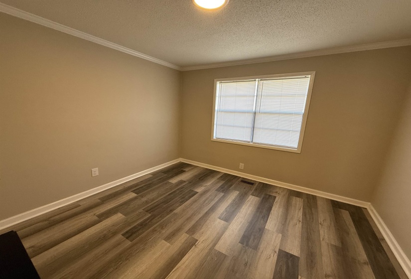Unfurnished room with dark wood-style floors, visible vents, a textured ceiling, and baseboards