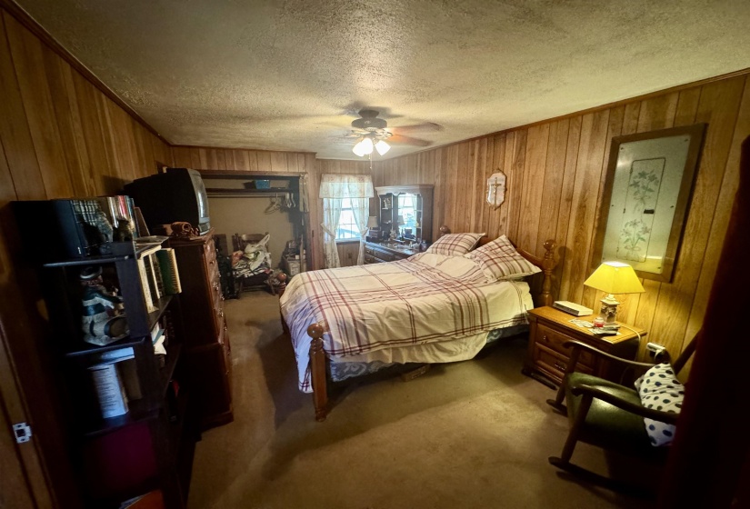 Bedroom with wooden walls, carpet floors, and a textured ceiling