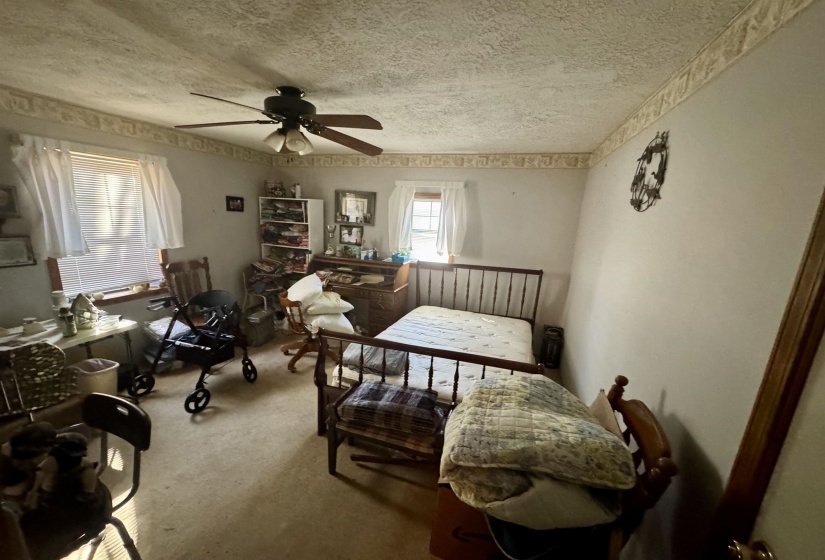 Carpeted bedroom with a textured ceiling and ceiling fan
