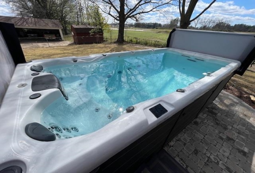 View of swimming pool featuring a storage shed, an outdoor structure, and a covered hot tub