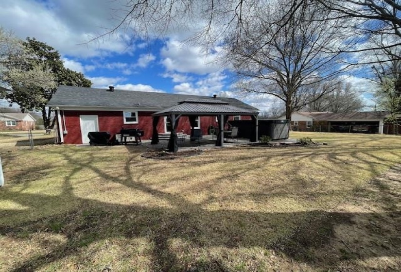 Rear view of house featuring a gazebo, a lawn, and a patio