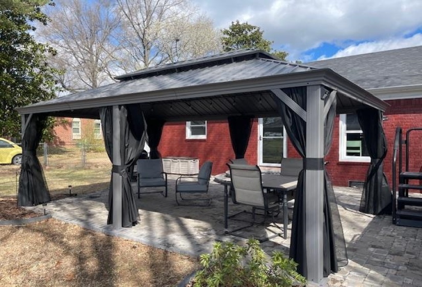 View of patio with a gazebo, outdoor dining area, and fence