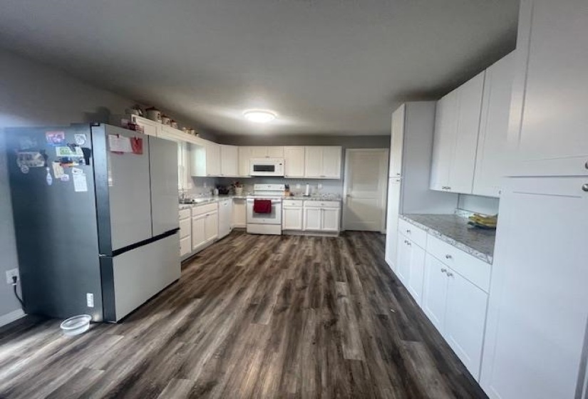 Kitchen featuring white appliances, dark wood-type flooring, and white cabinets
