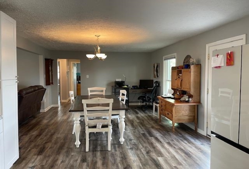 Dining area featuring dark wood finished floors, an inviting chandelier, baseboards, and a textured ceiling
