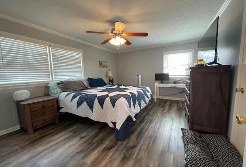 Bedroom featuring a textured ceiling, a ceiling fan, dark wood-style floors, and ornamental molding