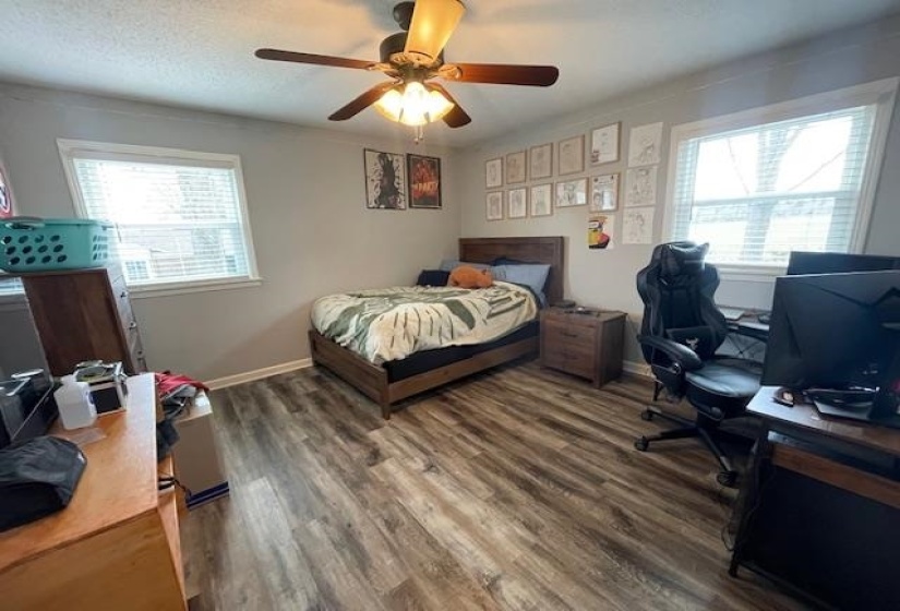 Bedroom with a textured ceiling, a ceiling fan, baseboards, and wood finished floors