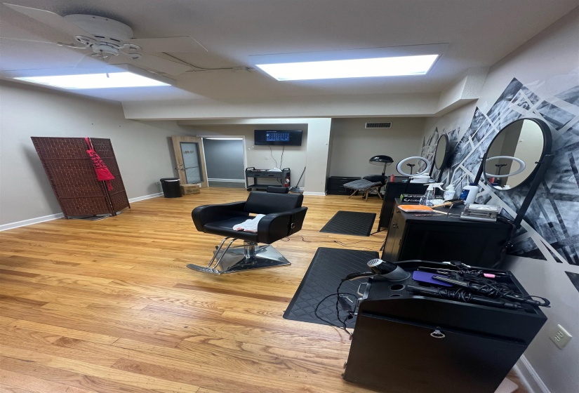 Workout area featuring ceiling fan, visible vents, baseboards, and wood finished floors