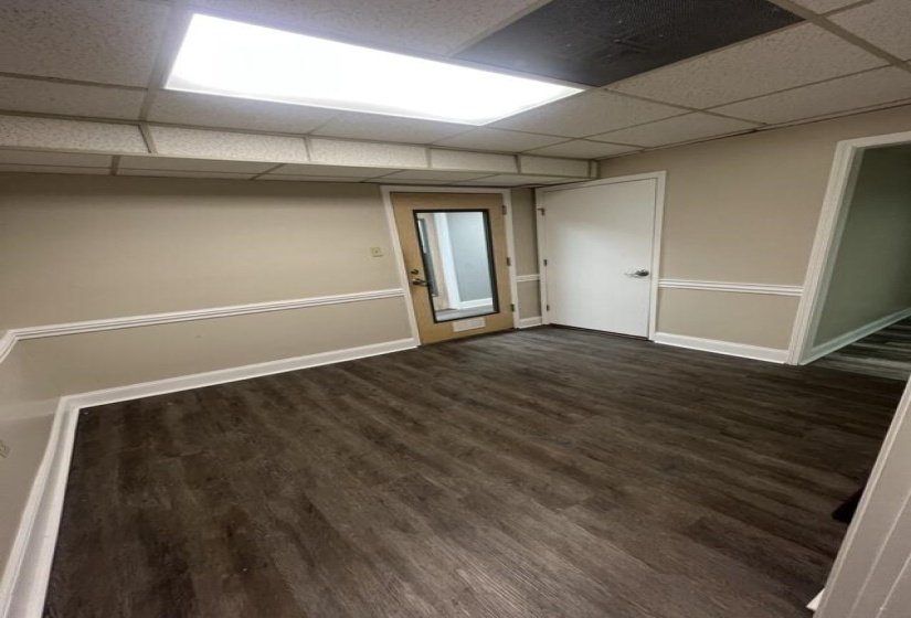 Unfurnished room with dark wood finished floors, a drop ceiling, and baseboards