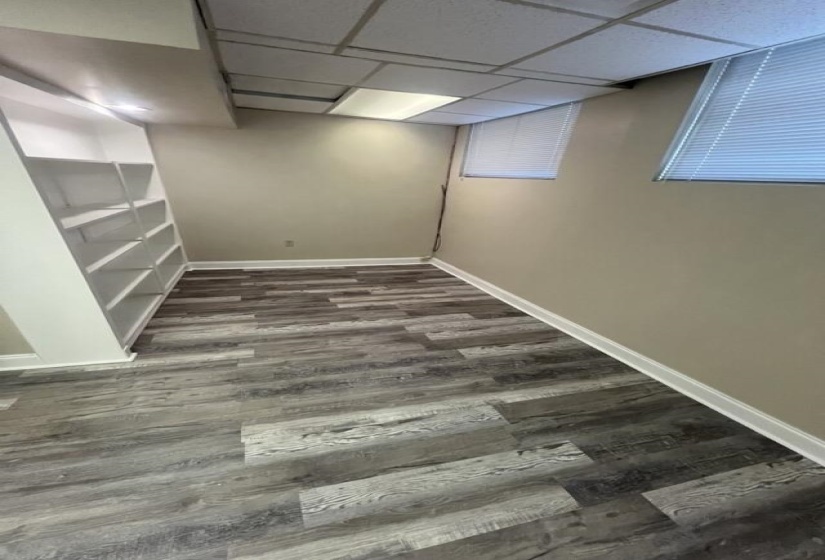 Finished below grade area with a paneled ceiling, baseboards, and dark wood finished floors