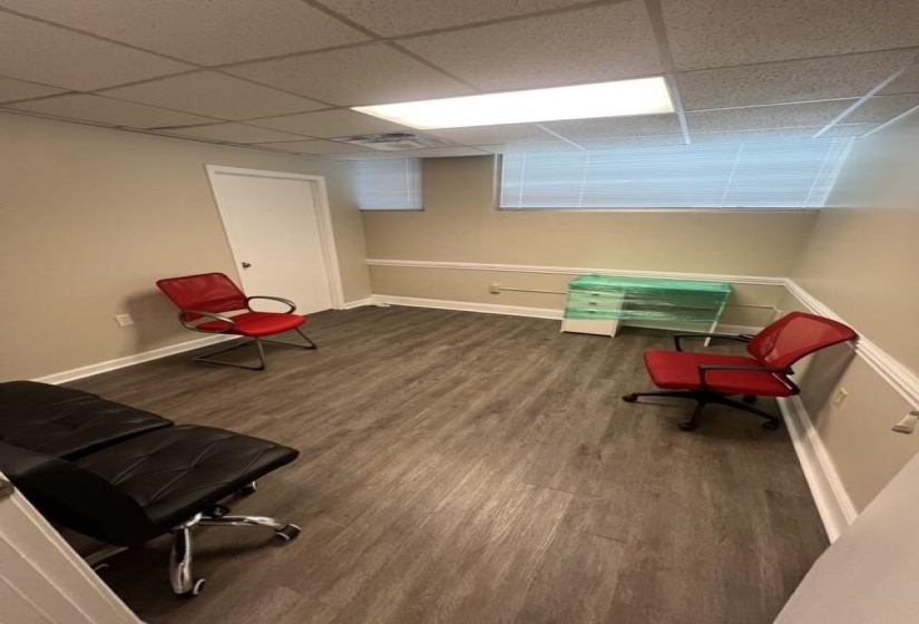 Living area with a drop ceiling, baseboards, and wood finished floors