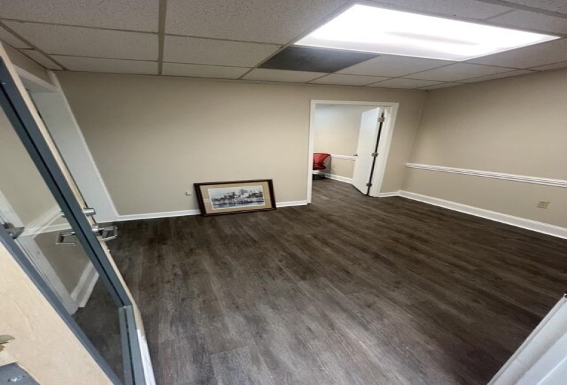 Spare room with baseboards, dark wood-style flooring, and a drop ceiling