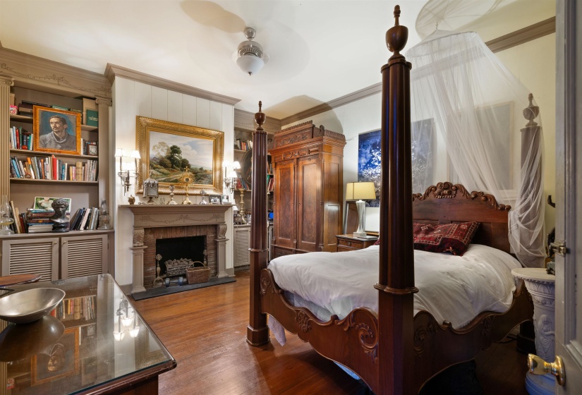 Bedroom with ceiling fan, ornamental molding, a fireplace, and wood-type flooring