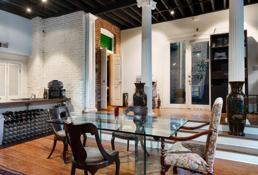 Dining space with french doors, decorative columns, brick wall, and hardwood / wood-style floors