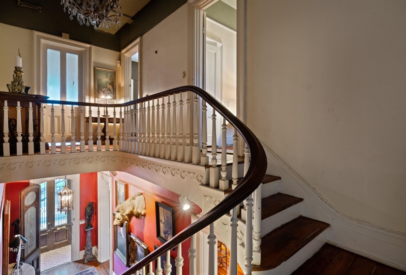 Staircase with a chandelier and wood-type flooring