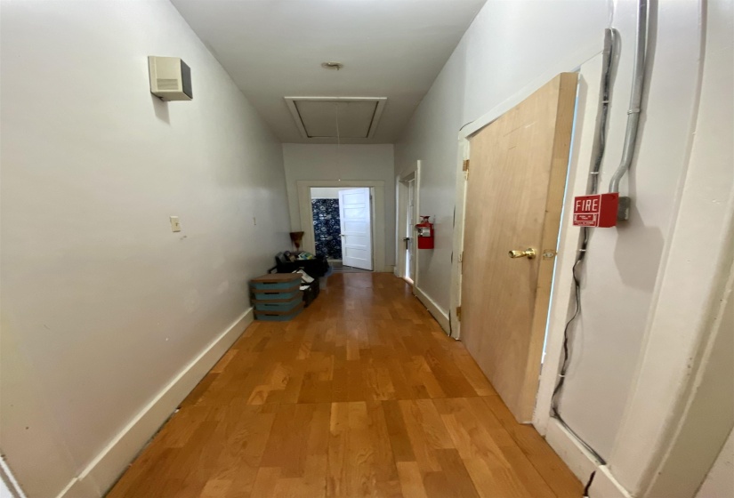 Corridor featuring light wood-style floors, baseboards, and attic access