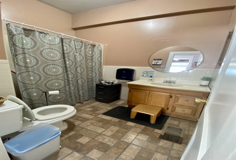 Full bathroom with tile walls, a wainscoted wall, visible vents, and toilet