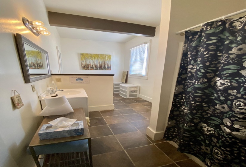Bathroom with baseboards, a sink, beam ceiling, double vanity, and curtained shower
