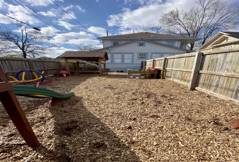 Back of property featuring a fenced backyard and a playground