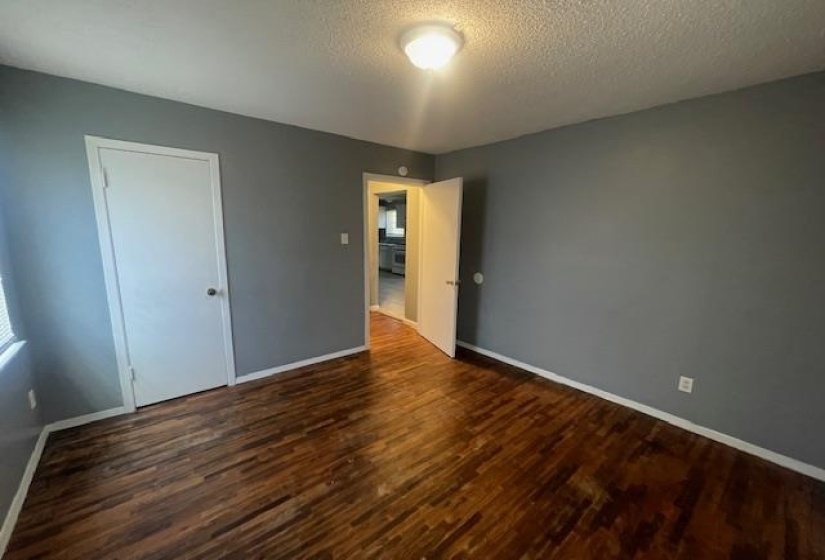 Unfurnished bedroom featuring a textured ceiling, baseboards, and wood finished floors