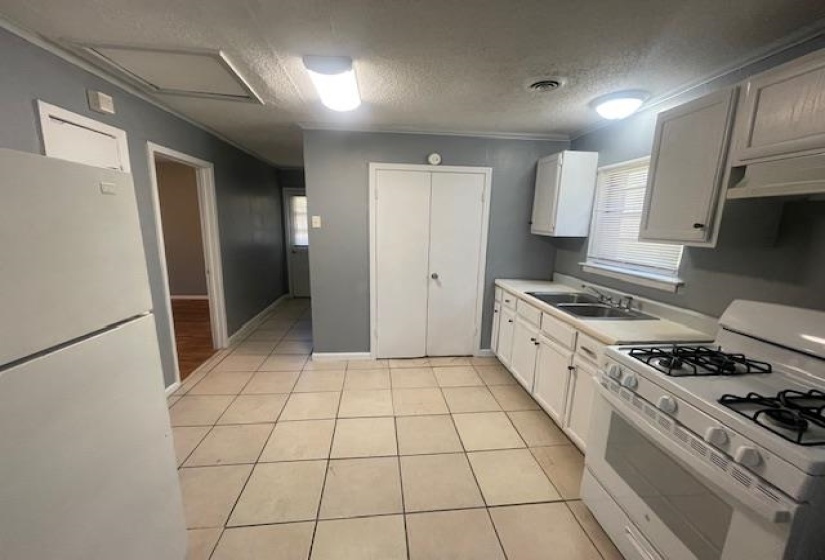 Kitchen with light countertops, white appliances, a textured ceiling, a sink, and light tile patterned flooring