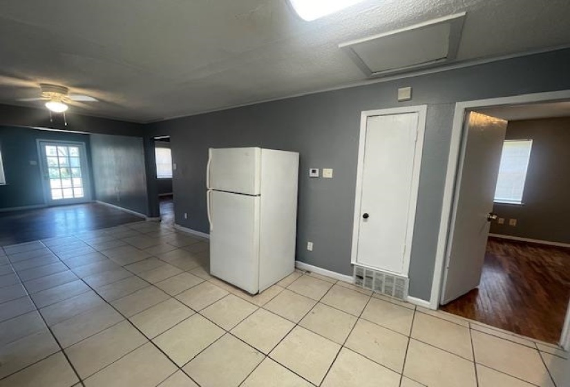 Kitchen with freestanding refrigerator, light tile patterned floors, baseboards, and a ceiling fan
